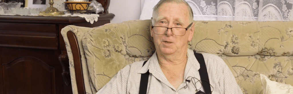 A retired priest seated in an armchair at home
