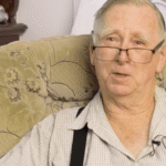 A retired priest seated in an armchair at home
