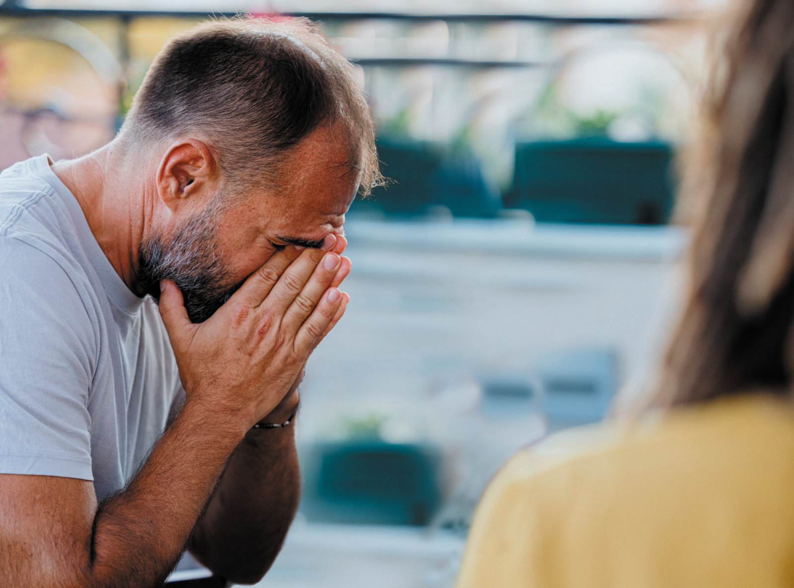 A man covering his face with his hands while talking with a support worker
