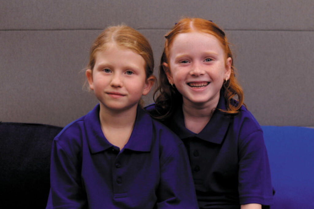 Two smiling schoolgirls in their school uniforms