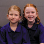 Two smiling schoolgirls in their school uniforms