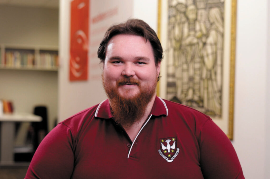 A smiling seminarian in a Holy Spirit Seminary polo shirt