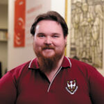 A smiling seminarian in a Holy Spirit Seminary polo shirt