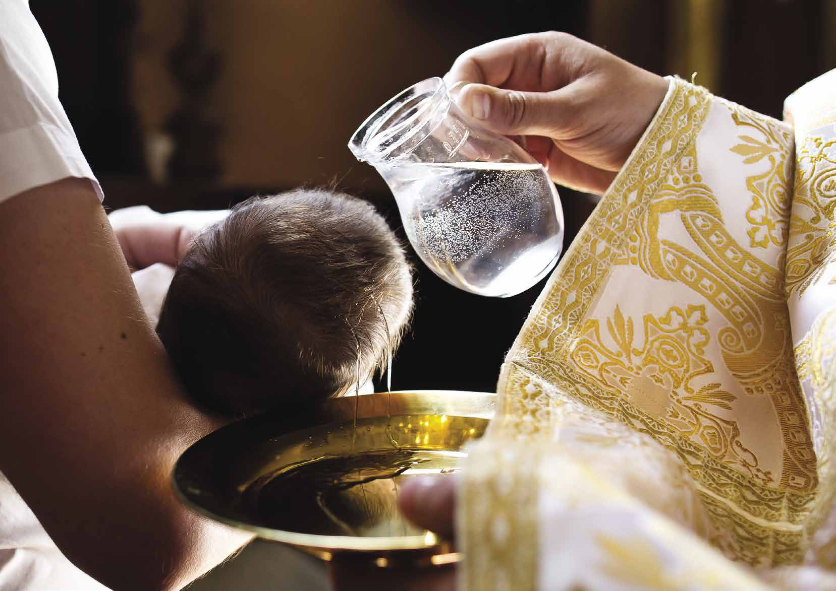A priest pouring baptismal water over a child's head