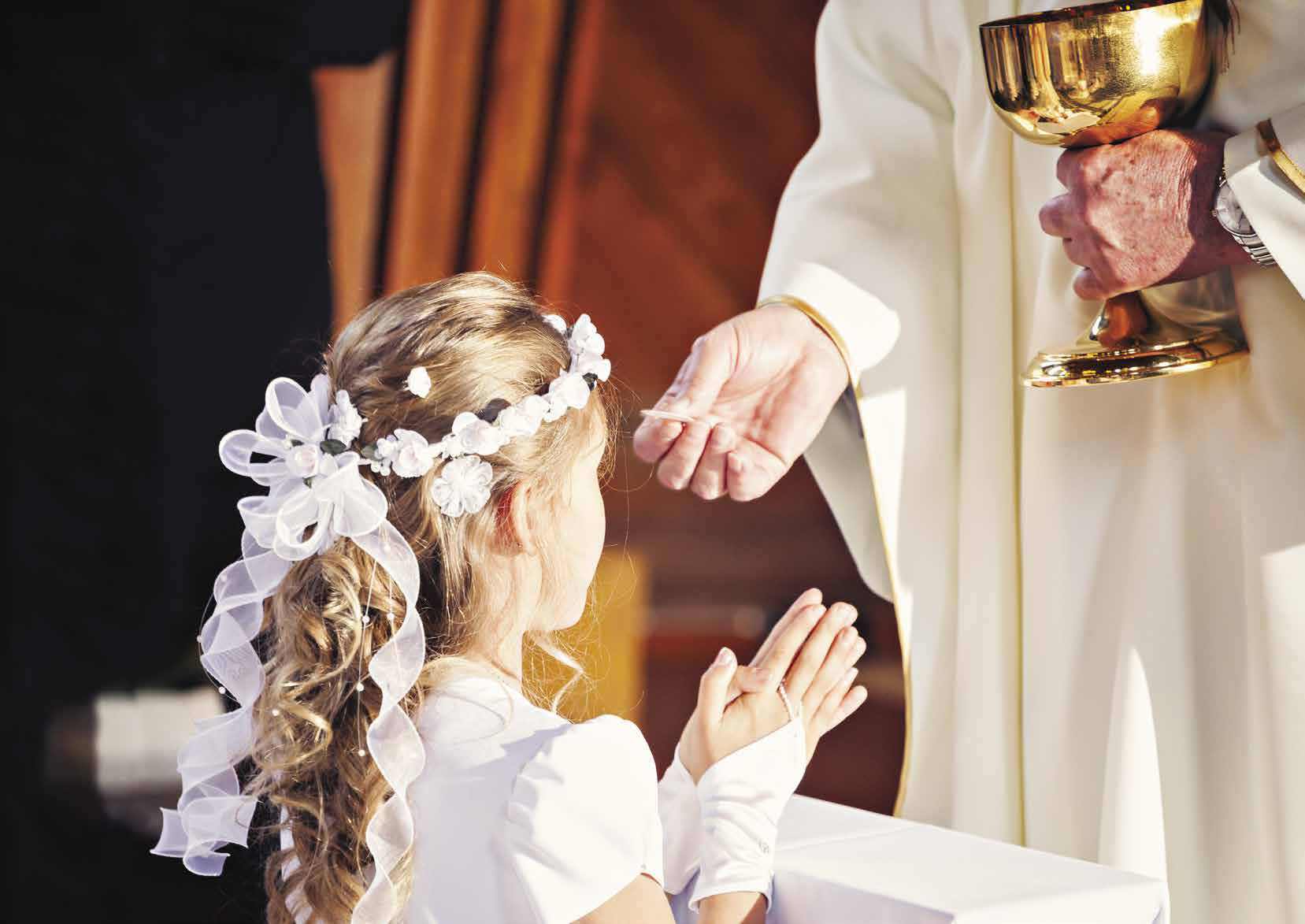 A young girl in white receiving her First Communion