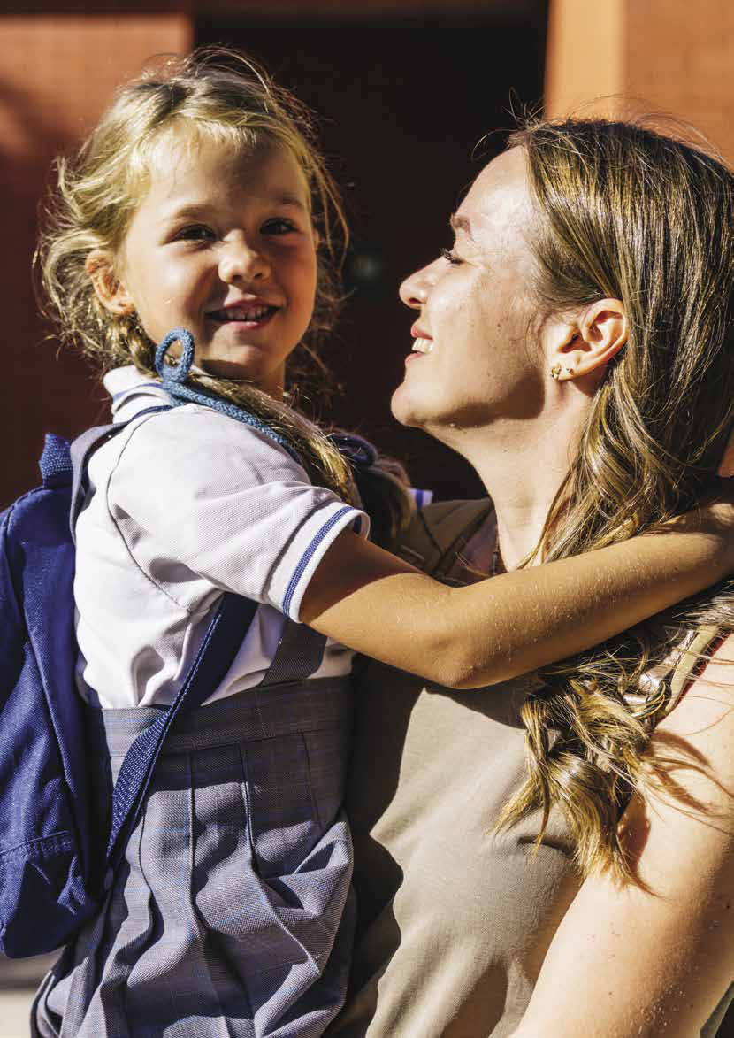A smiling girl in school uniform hugging her mother